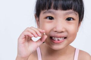 young girl holding her missing tooth
